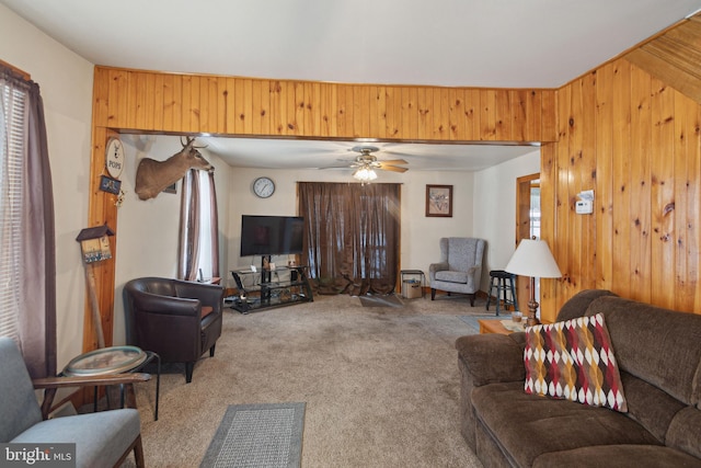 carpeted living room with ceiling fan and wooden walls