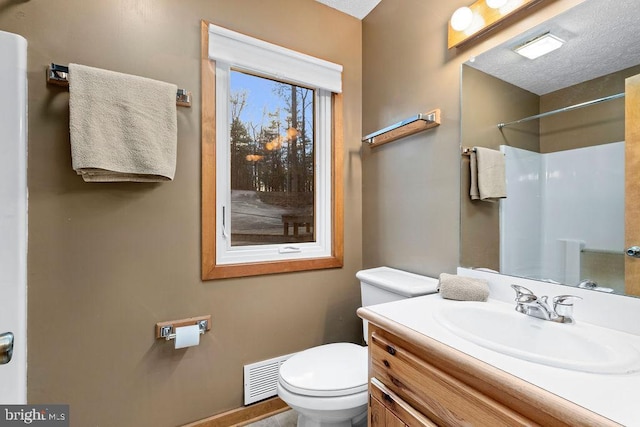 bathroom with vanity, a shower, a textured ceiling, and toilet