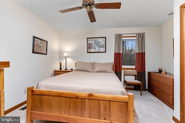 bedroom with ceiling fan, light colored carpet, and a textured ceiling