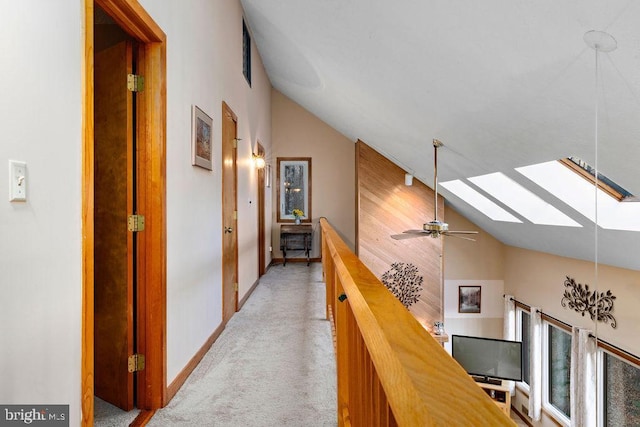 hall featuring light colored carpet, high vaulted ceiling, and a skylight