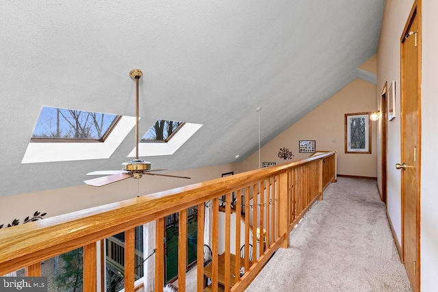 hallway with light carpet and vaulted ceiling with skylight