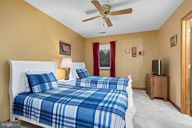 bedroom featuring a textured ceiling, light colored carpet, and ceiling fan