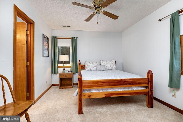 carpeted bedroom featuring ceiling fan and a textured ceiling