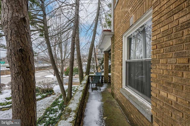 view of snowy exterior featuring brick siding