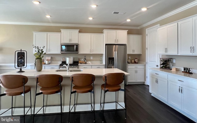 kitchen featuring dark hardwood / wood-style flooring, stainless steel appliances, white cabinetry, and a center island with sink