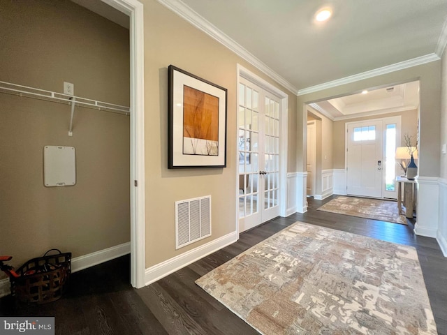 foyer with ornamental molding, a raised ceiling, french doors, and dark wood-type flooring