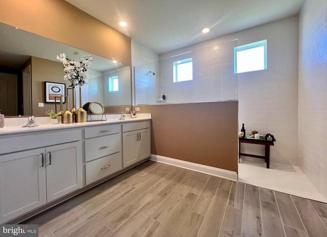 bathroom with tiled shower, vanity, and hardwood / wood-style flooring