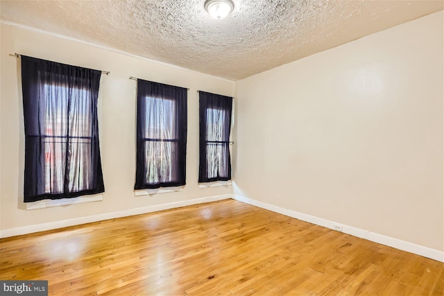 unfurnished room with wood-type flooring and a textured ceiling