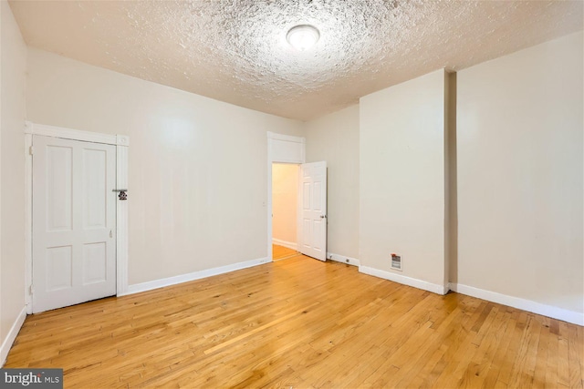 spare room with a textured ceiling and light hardwood / wood-style flooring