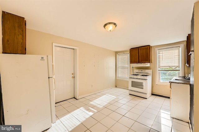 kitchen with light tile patterned flooring, white appliances, and sink