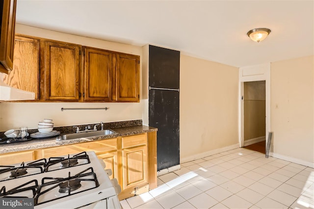 kitchen with light tile patterned floors, gas range gas stove, and sink