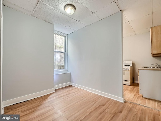 unfurnished room featuring a paneled ceiling, light hardwood / wood-style floors, and sink