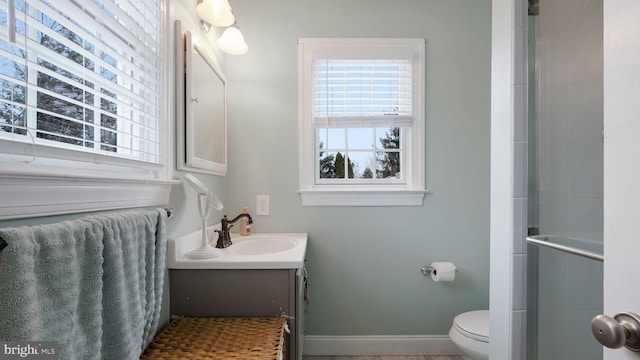 bathroom featuring a shower with door, toilet, and vanity