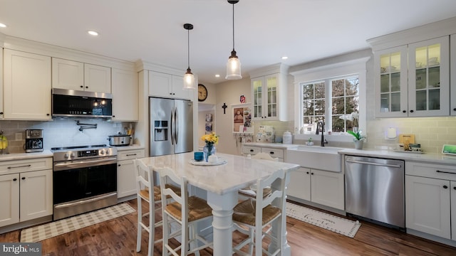 kitchen featuring white cabinets, decorative light fixtures, stainless steel appliances, decorative backsplash, and sink