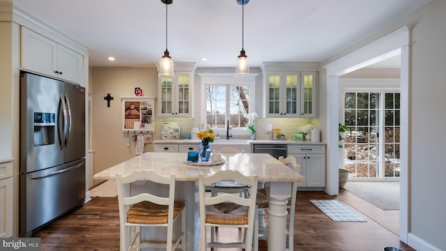 kitchen featuring pendant lighting, white cabinets, a kitchen island, decorative backsplash, and stainless steel fridge with ice dispenser