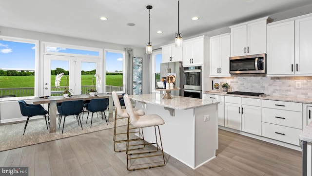 kitchen with white cabinets, appliances with stainless steel finishes, a center island, and hanging light fixtures