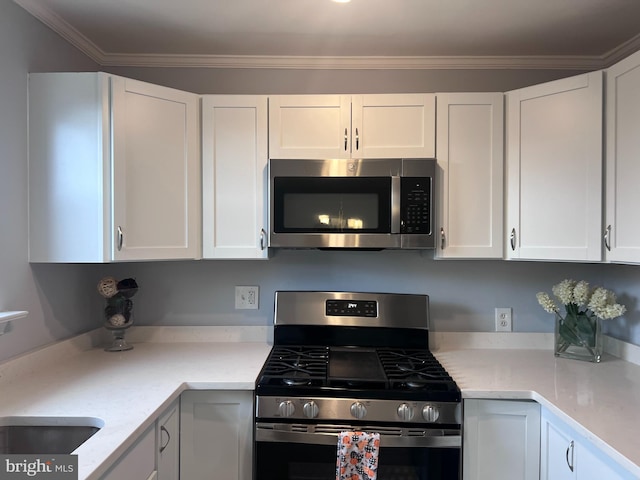 kitchen featuring light stone countertops, stainless steel appliances, white cabinetry, and ornamental molding