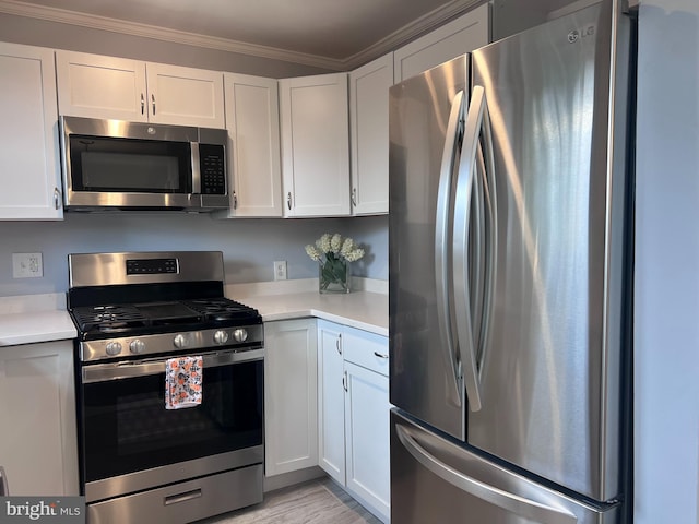 kitchen featuring white cabinetry, ornamental molding, light wood-type flooring, and appliances with stainless steel finishes