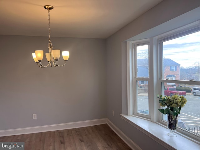 unfurnished dining area featuring dark hardwood / wood-style floors and an inviting chandelier