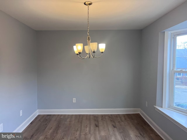 spare room featuring a chandelier and dark hardwood / wood-style floors