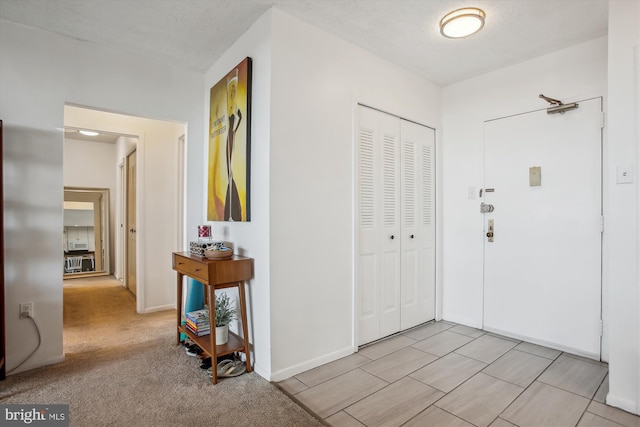 entryway featuring light colored carpet and a textured ceiling