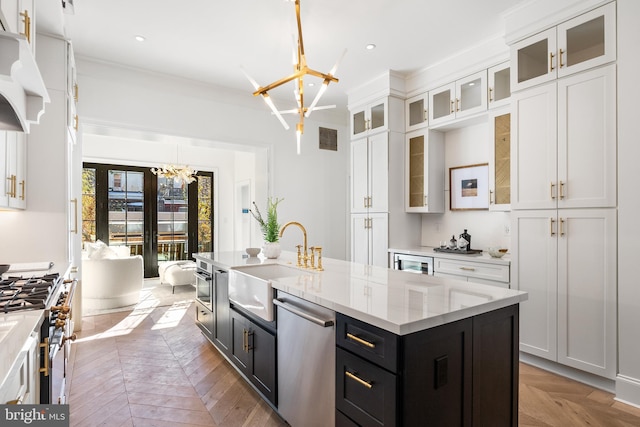 kitchen with parquet flooring, sink, stainless steel appliances, a center island with sink, and an inviting chandelier