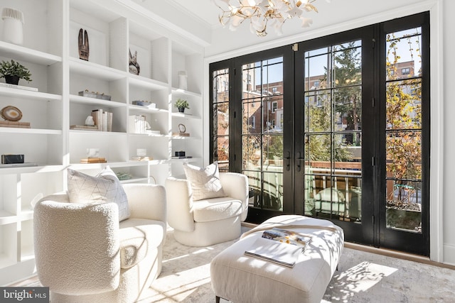 sitting room with crown molding, a notable chandelier, built in shelves, and french doors