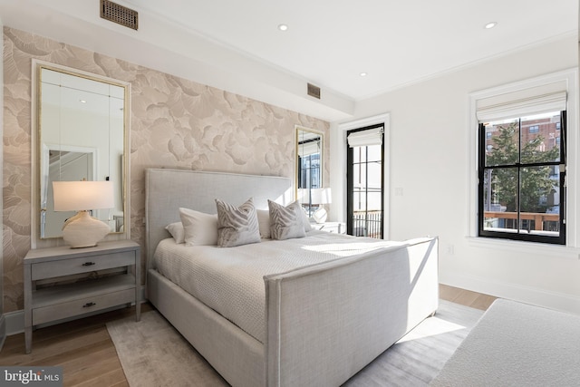 bedroom featuring multiple windows, crown molding, and light hardwood / wood-style floors