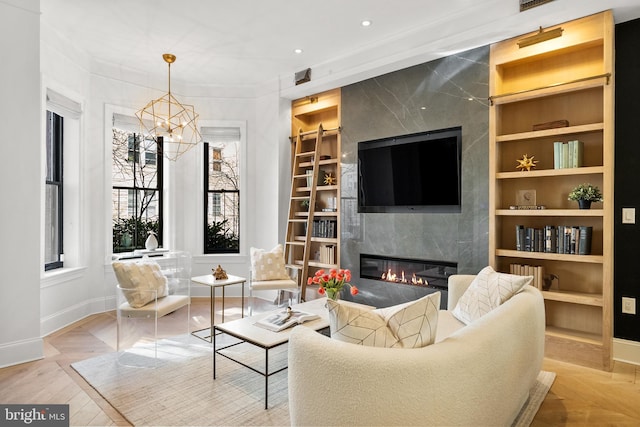 living room featuring built in shelves, a fireplace, and an inviting chandelier