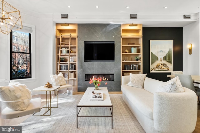 living room featuring an inviting chandelier, a premium fireplace, and built in features