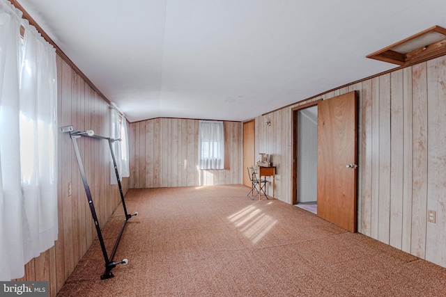 interior space with wood walls, light colored carpet, and vaulted ceiling