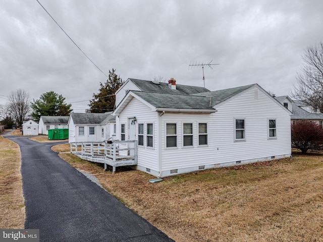 view of front of house with an outbuilding, a front yard, and a deck