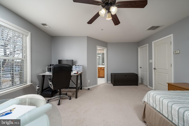 bedroom with connected bathroom, light colored carpet, and ceiling fan