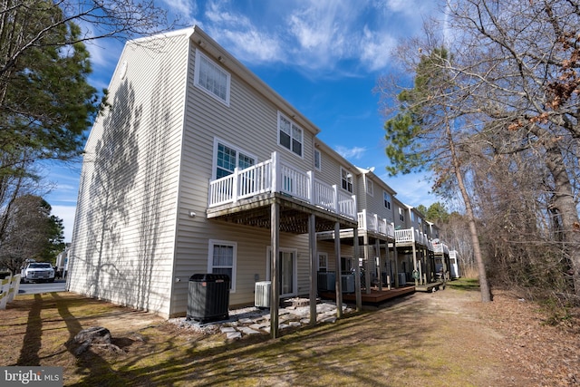 rear view of house featuring a wooden deck and cooling unit