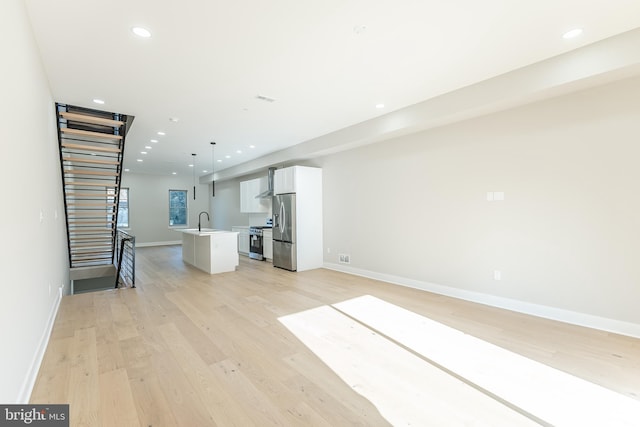 unfurnished living room featuring sink and light hardwood / wood-style flooring