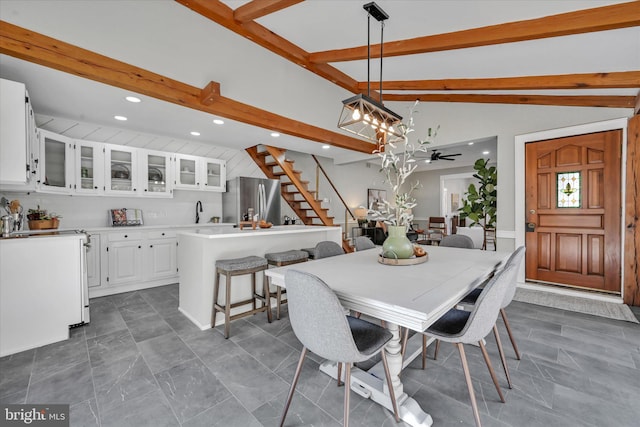 dining space featuring ceiling fan with notable chandelier, vaulted ceiling with beams, and sink