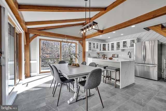 dining room featuring vaulted ceiling with beams, sink, and a chandelier