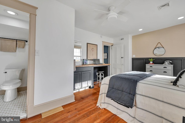 bedroom with light wood-type flooring, ceiling fan, and connected bathroom