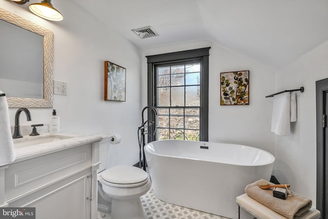 bathroom featuring a tub to relax in, tile patterned floors, lofted ceiling, toilet, and vanity