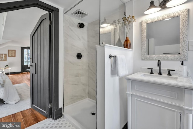 bathroom with tiled shower, wood-type flooring, and vanity