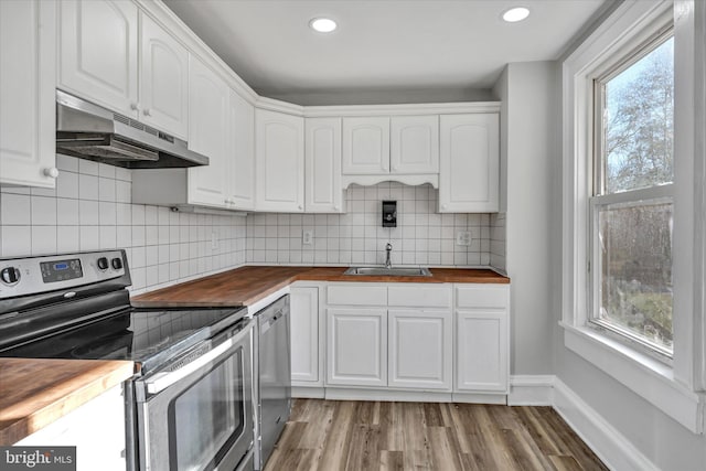 kitchen featuring white cabinetry, sink, stainless steel appliances, butcher block countertops, and light hardwood / wood-style floors