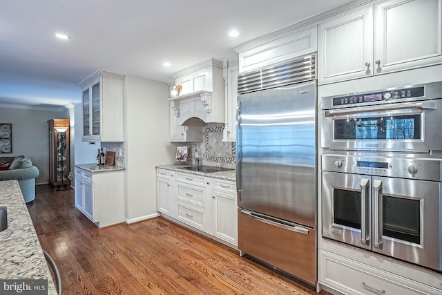 kitchen featuring decorative backsplash, appliances with stainless steel finishes, white cabinetry, and light stone countertops