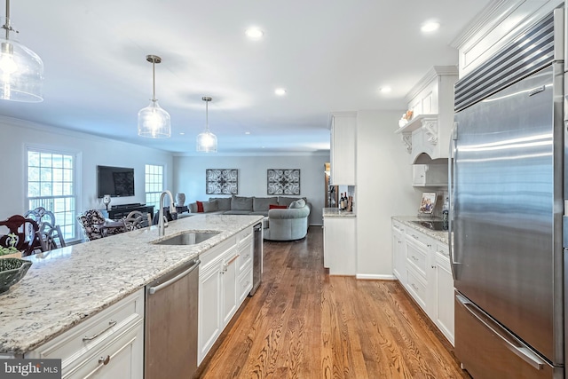 kitchen with decorative light fixtures, sink, white cabinetry, and stainless steel appliances