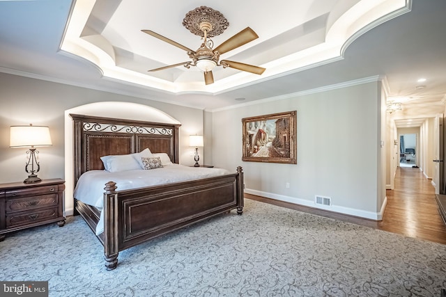 bedroom with a raised ceiling, ceiling fan, light hardwood / wood-style flooring, and ornamental molding