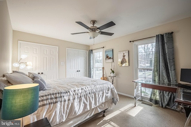 carpeted bedroom featuring ceiling fan, multiple closets, and multiple windows