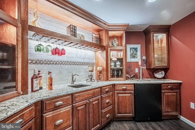 bar featuring dark hardwood / wood-style flooring, light stone countertops, and sink