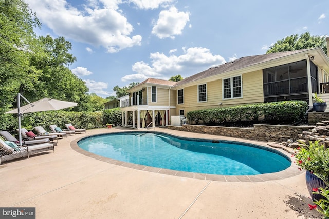 view of swimming pool with a sunroom and a patio