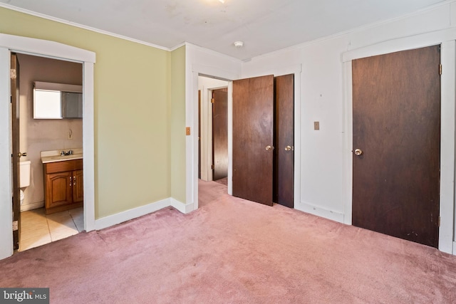 unfurnished bedroom with crown molding, light colored carpet, connected bathroom, and sink