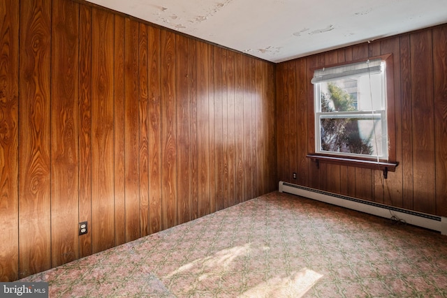 carpeted empty room featuring baseboard heating and wooden walls