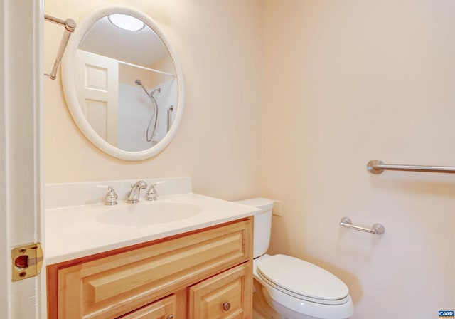 bathroom with walk in shower, vanity, and toilet